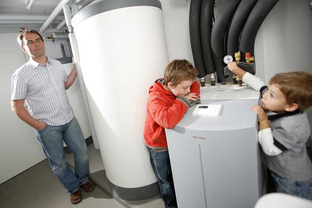 Two kids playing around a furnace with their father watching