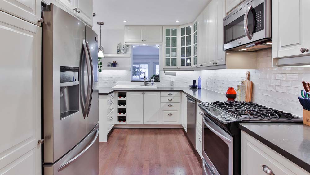 A kitchen with white cabinets, a french door refrigerator, oven, microwave, dishwasher and sink